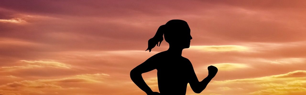 silhouette of a woman running at the beach during sunset